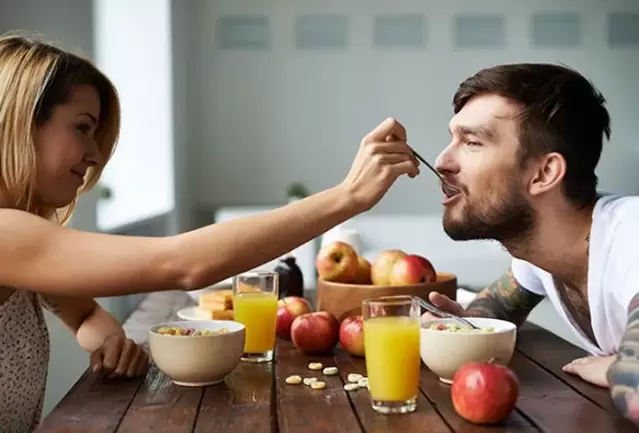a woman feeds a man with nuts to increase his potency
